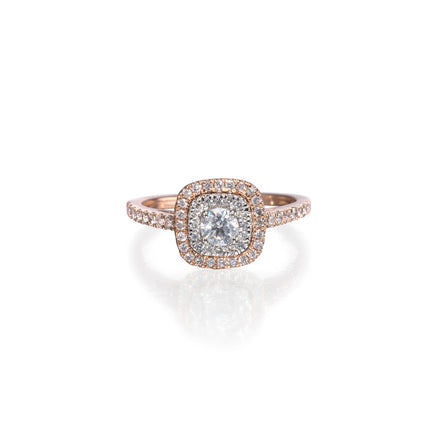 A square cushion-cut halo ring featuring a central round brilliant-cut diamond surrounded by a halo of small pavé diamonds, set in rose gold with a matching pavé band, shown on a white background with a soft reflection.
