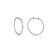 A pair of white gold hoop earrings with a textured, rope-like outer surface paved with small clear stones, shown on a white background with a soft reflection.