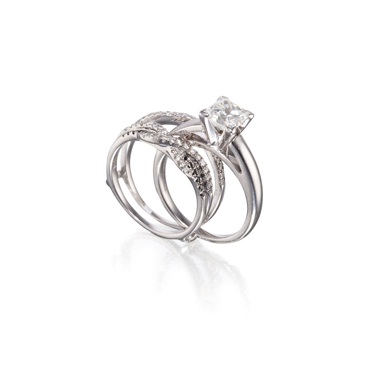 A white gold wedding ring set featuring a solitaire engagement ring with a rectangular clear gemstone and a matching band with pavé-set clear stones, displayed on a clean white background with a soft reflection.