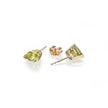 Gold earrings with green gemstones on a white background