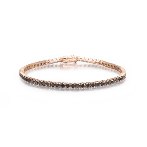 A delicate tennis bracelet in rose gold with a row of small dark round-cut diamond stones, displayed on a clean white background.