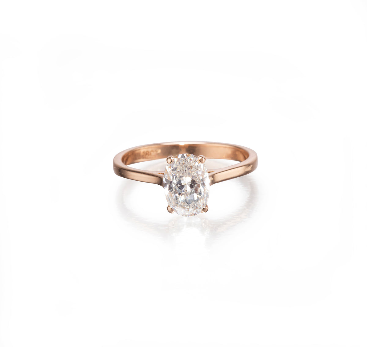 A rose gold engagement ring featuring an oval-cut diamond set in a four-prong setting, shown on a clean white background with a soft reflection.
