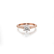 A rose gold engagement ring featuring a round-cut center stone in a prong setting, with a pavé band accented by small round stones, shown on a clean white background with a soft reflection.