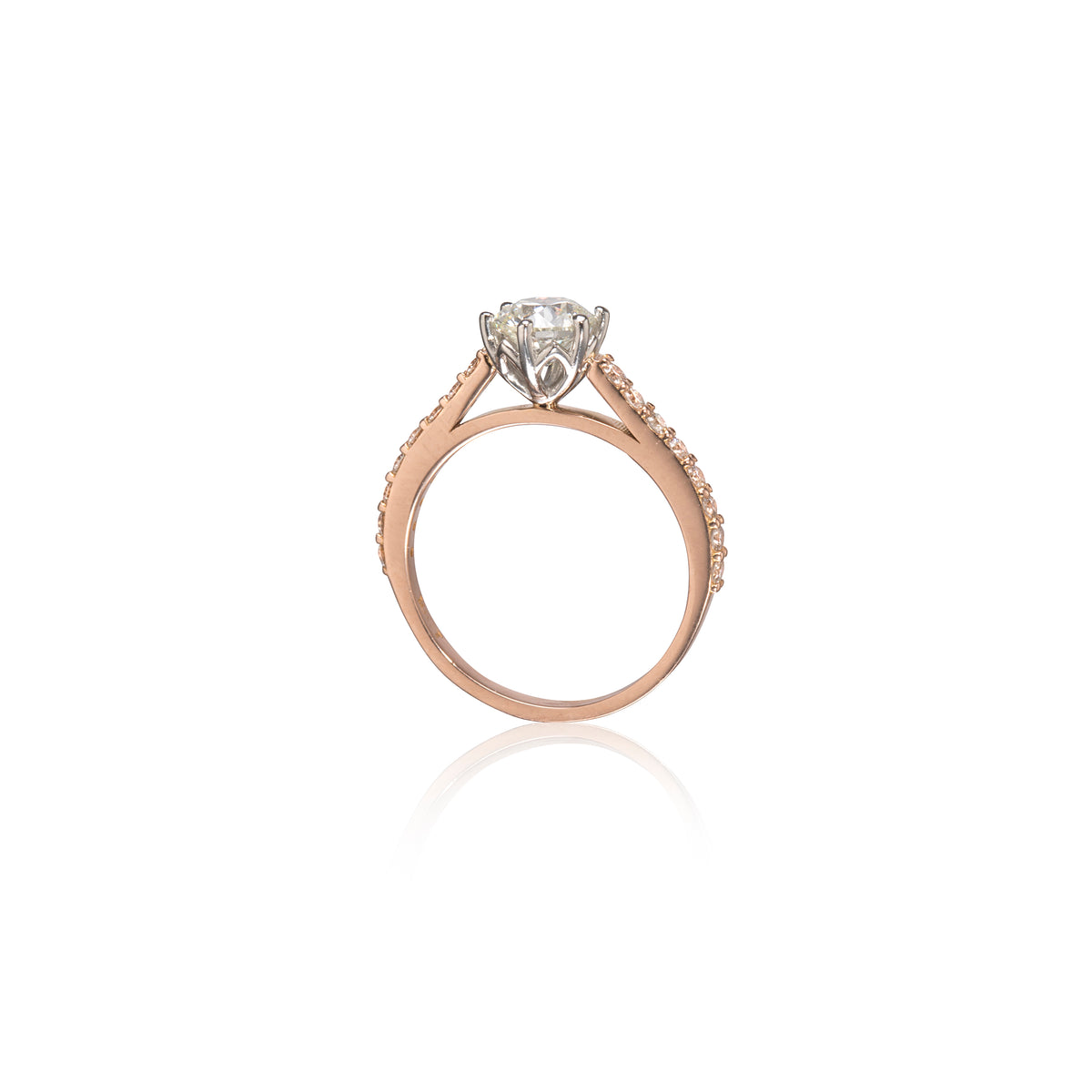 A rose gold engagement ring featuring a round-cut diamond center stone in a four-prong setting, with small pavé diamonds, shown on a clean white background with a soft reflection.