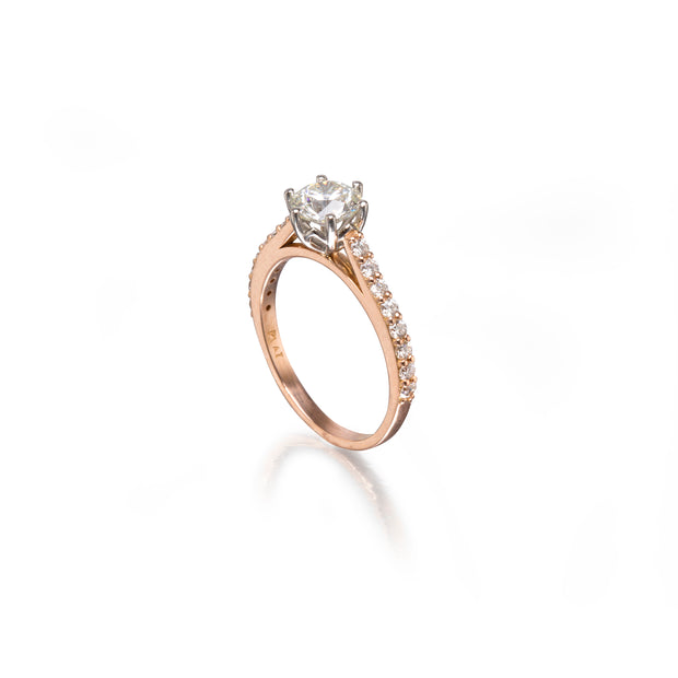 A rose gold engagement ring featuring a clear center stone and a pavé band with small round stones, set against a clean white background with a soft reflection.