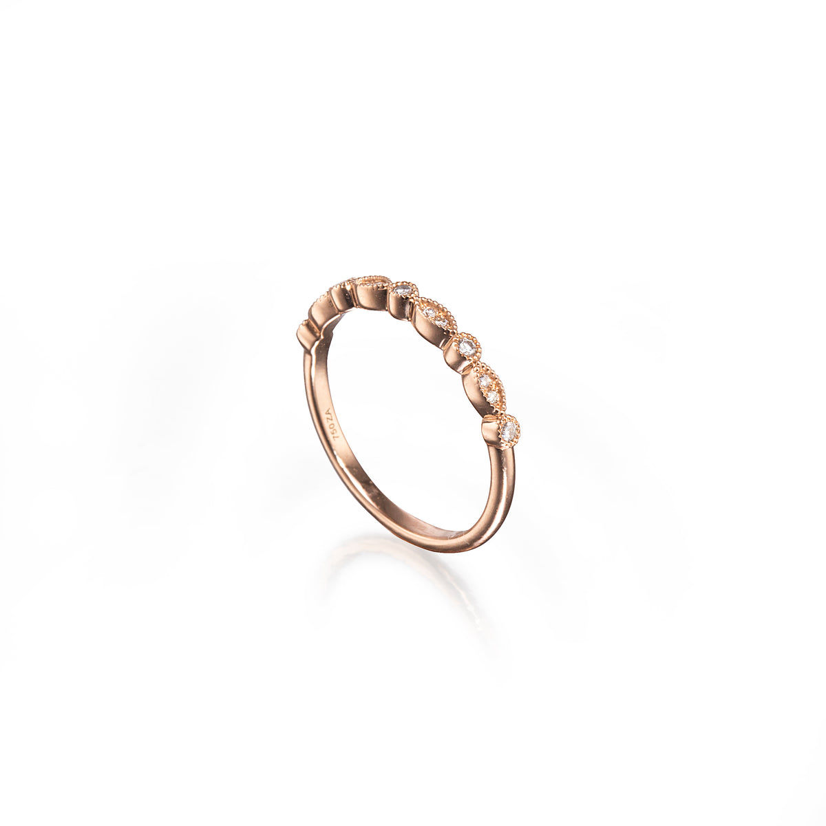 A rose gold eternity-style ring featuring a row of small clear gemstones set in a wavy, textured band, photographed on a clean white background with a soft reflection.