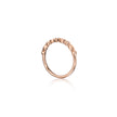 A rose gold ring with a textured, beaded outer band and small clear stones set along the top, shown on a clean white background with a soft reflection below.