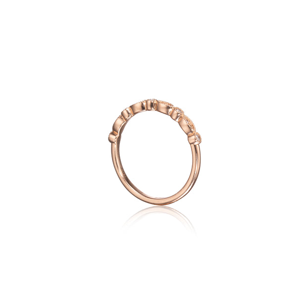 A rose gold ring with a textured, beaded outer band and small clear stones set along the top, shown on a clean white background with a soft reflection below.