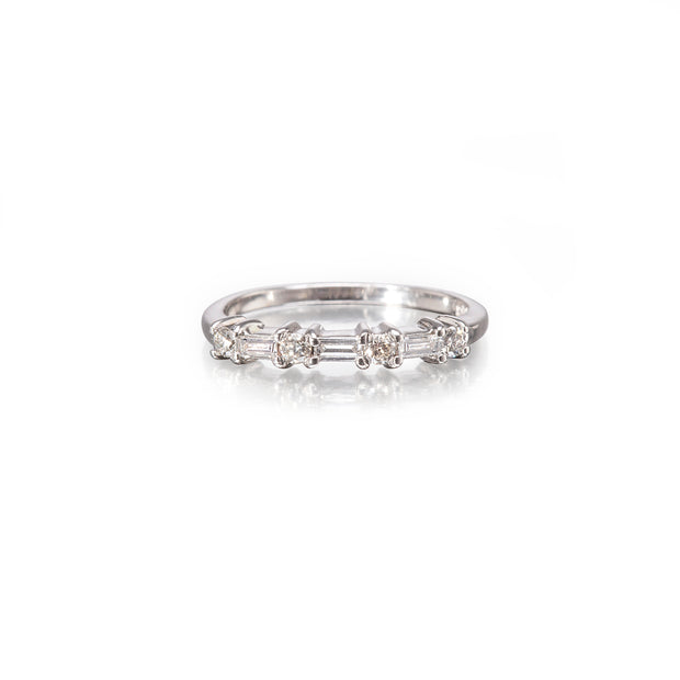 A white gold diamond band ring featuring a row of baguette-cut and round diamonds on a plain white background.