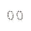 A pair of white gold hoop earrings with a row of clear stones along the front, displayed on a clean white background with a soft reflection below.