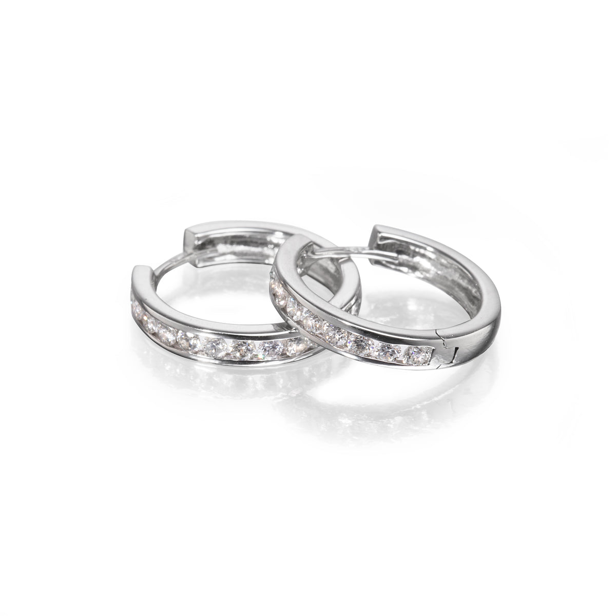 A pair of white gold huggie hoop earrings with a channel-set row of clear cubic zirconia stones, displayed on a clean white reflective surface.