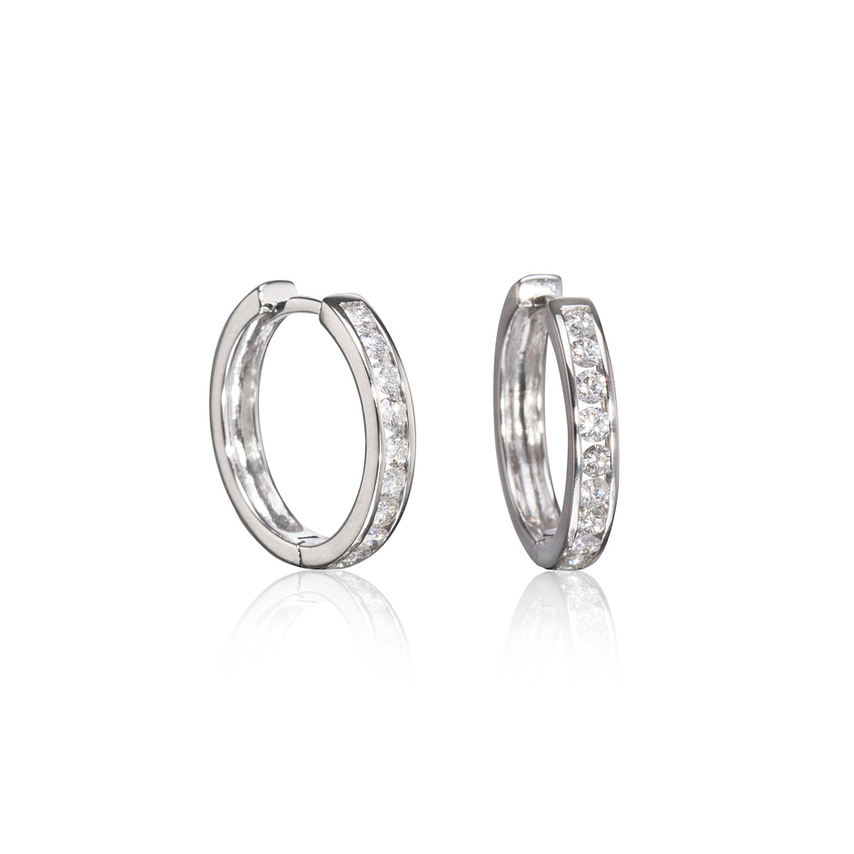 A pair of white gold hoop earrings with a channel setting of clear stones, displayed on a clean white background with a soft reflection below.