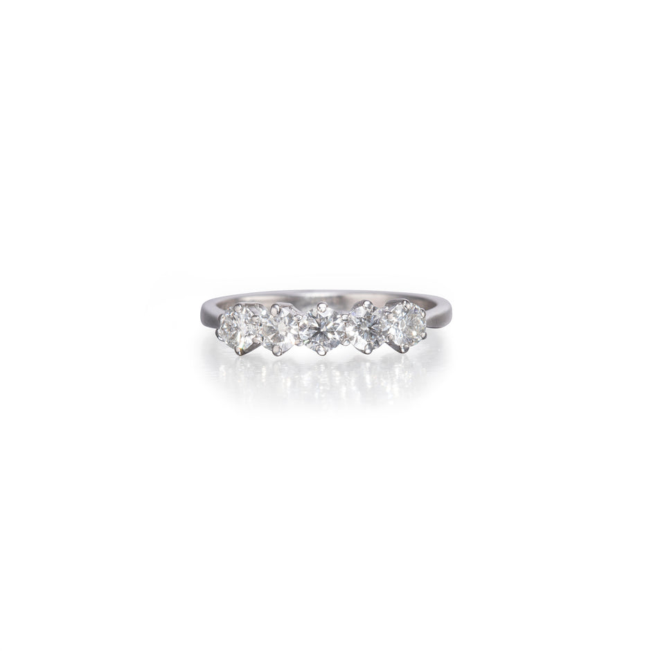 A white gold five-stone diamond ring with five round-cut diamonds set in a polished band, shown on a clean white background with a soft reflection below.
