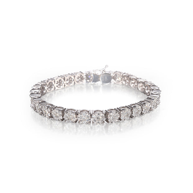 A white gold tennis bracelet with round-cut clear stones, photographed on a reflective white surface against a white background.