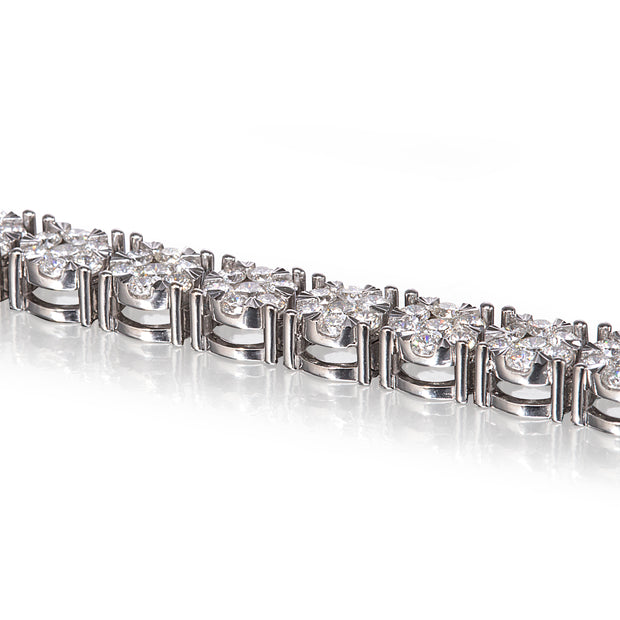 A close-up of a tennis bracelet featuring clear round-cut gemstones in a white gold setting, shown against a bright white background with a soft reflection.