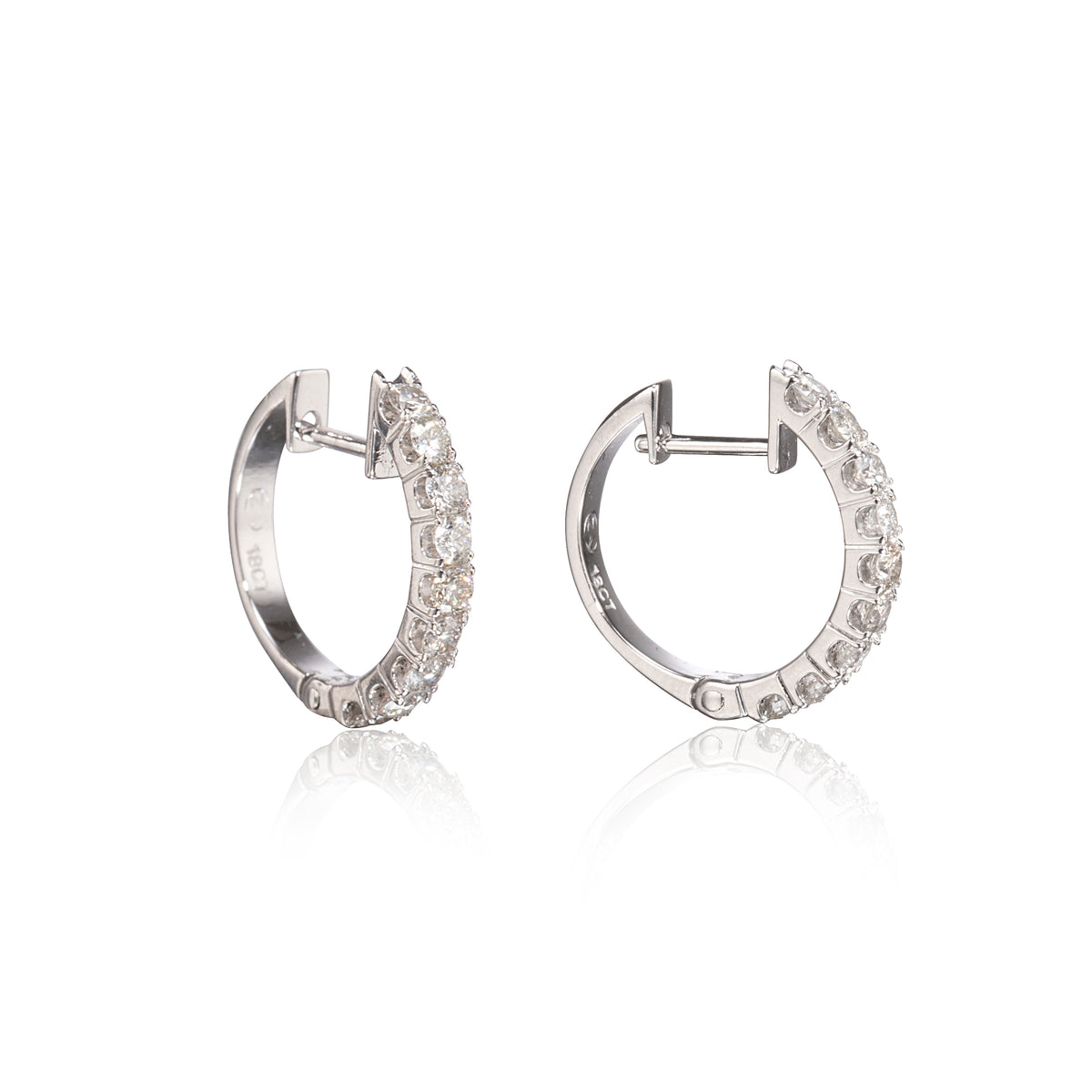 A pair of white gold hoop earrings with clear pavé-set stones, shown from the side on a white background with a soft reflection below.