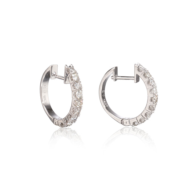 A pair of white gold hoop earrings with clear pavé-set stones, shown from the side on a white background with a soft reflection below.
