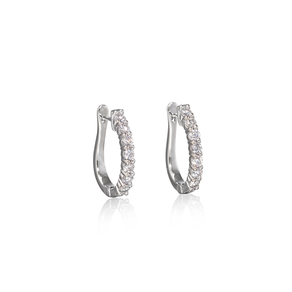 Pair of white gold hoop earrings with clear stones on a white background