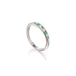 A white gold band ring featuring a row of small green emerald-cut gemstones and clear accent stones, shown on a clean white background with a soft reflection.