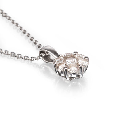 A white gold diamond cluster pendant necklace on a delicate chain, set against a clean white background with a soft reflection.