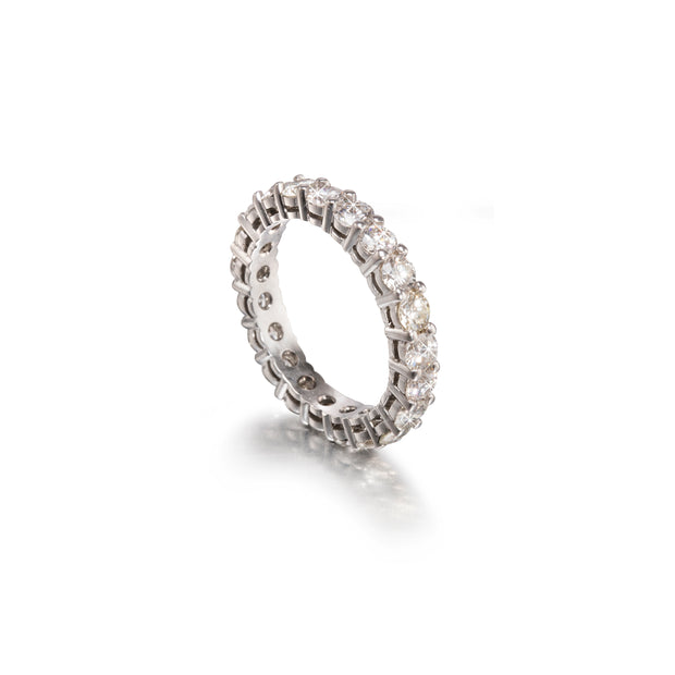 A diamond eternity ring in a white gold metal setting, shown on a clean white background with a soft reflection.