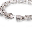 A close-up of a white gold pavé chain bracelet with a lobster clasp, showing the detailed metalwork and clear stone setting on a reflective white surface.