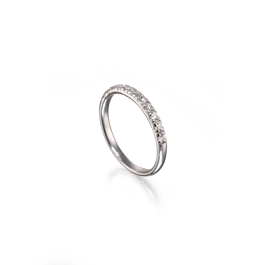 A white gold half-ring band featuring a row of small clear gemstones on one half, displayed on a clean white background with a soft reflection.