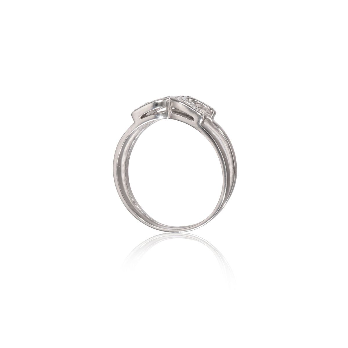 A white gold diamond ring shown from a side profile view on a clean white background with a soft reflection below.