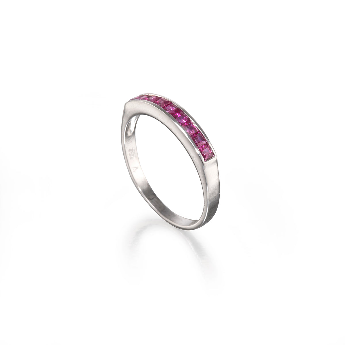 A white gold band ring featuring a channel setting of bright pink round-cut gemstones along the top curve, shown on a clean white background with a soft reflection.