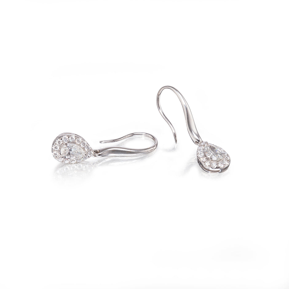 Pair of white gold teardrop earrings on a white background