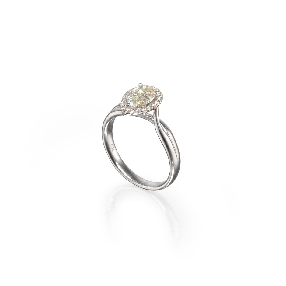 A white gold ring featuring a marquise-cut diamond center stone surrounded by a halo of smaller round diamonds, set on a split shank band, shown on a white background with a soft reflection.
