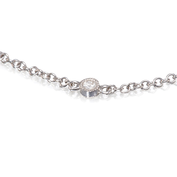 A close-up of a white gold and diamonds chain necklace with a central oval bezel-set clear gemstone, shown on a reflective white background.