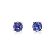 A pair of round-cut stud earrings featuring deep blue-purple tanzanite's in a four-prong setting, displayed on a clean white background with soft reflections below.