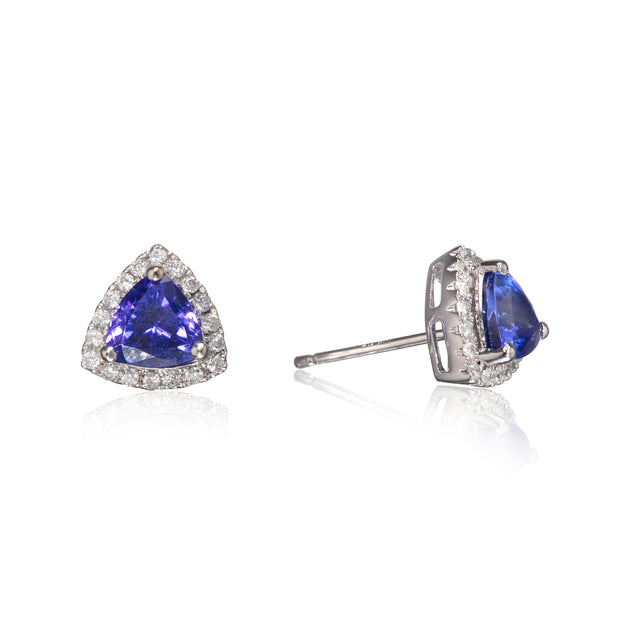 A pair of triangular stud earrings featuring a central blue sapphire stone surrounded by a halo of small clear stones in a white gold setting, shown on a white reflective background.