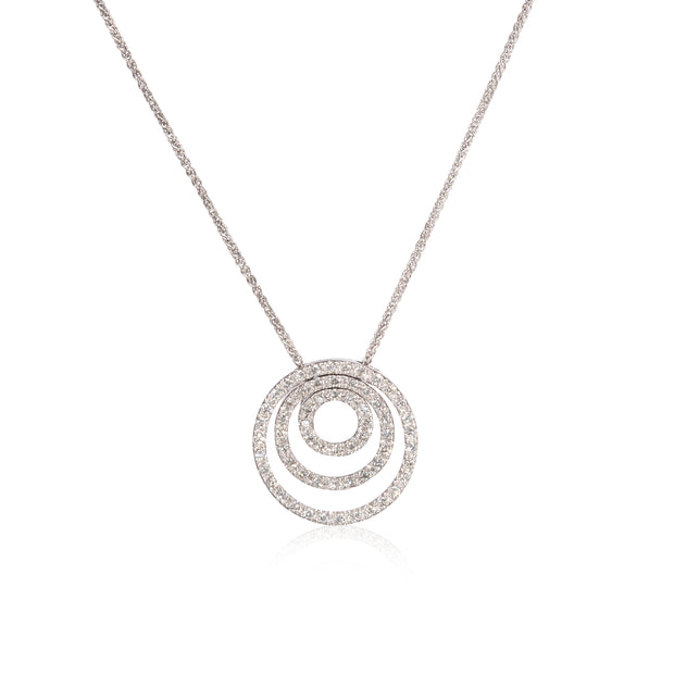 A white gold necklace featuring a multi-ring concentric spiral pendant paved with small clear stones, displayed on a clean white background with a soft reflection.