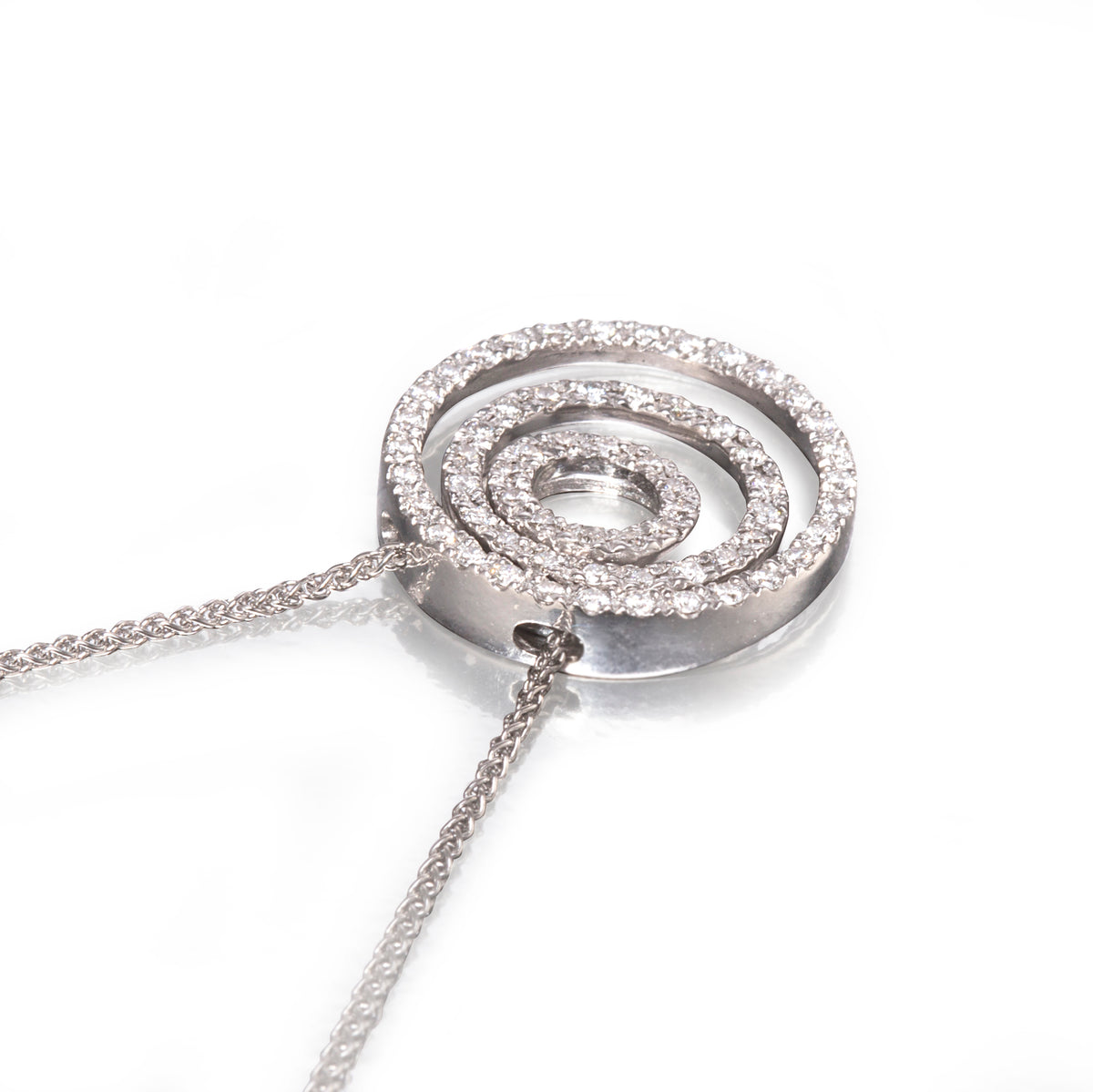 A white gold spiral pendant necklace paved with clear stones, shown on a clean white background.