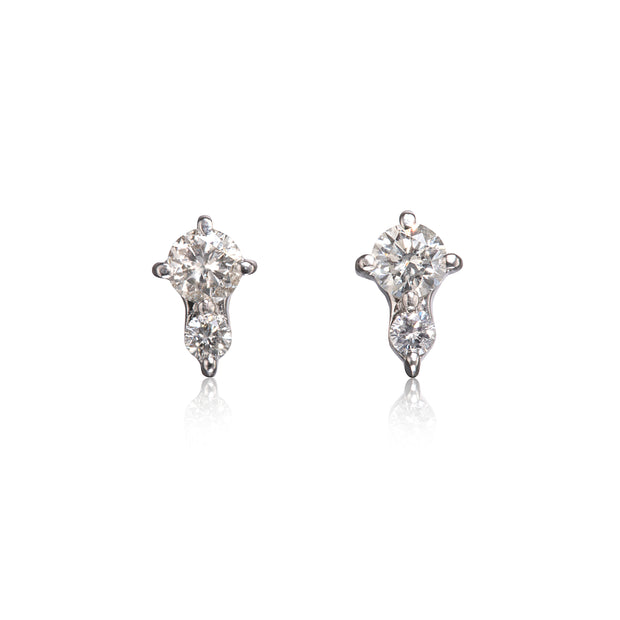 A pair of white gold stud earrings with round-cut clear gemstones, displayed on a clean white background with soft reflections below.