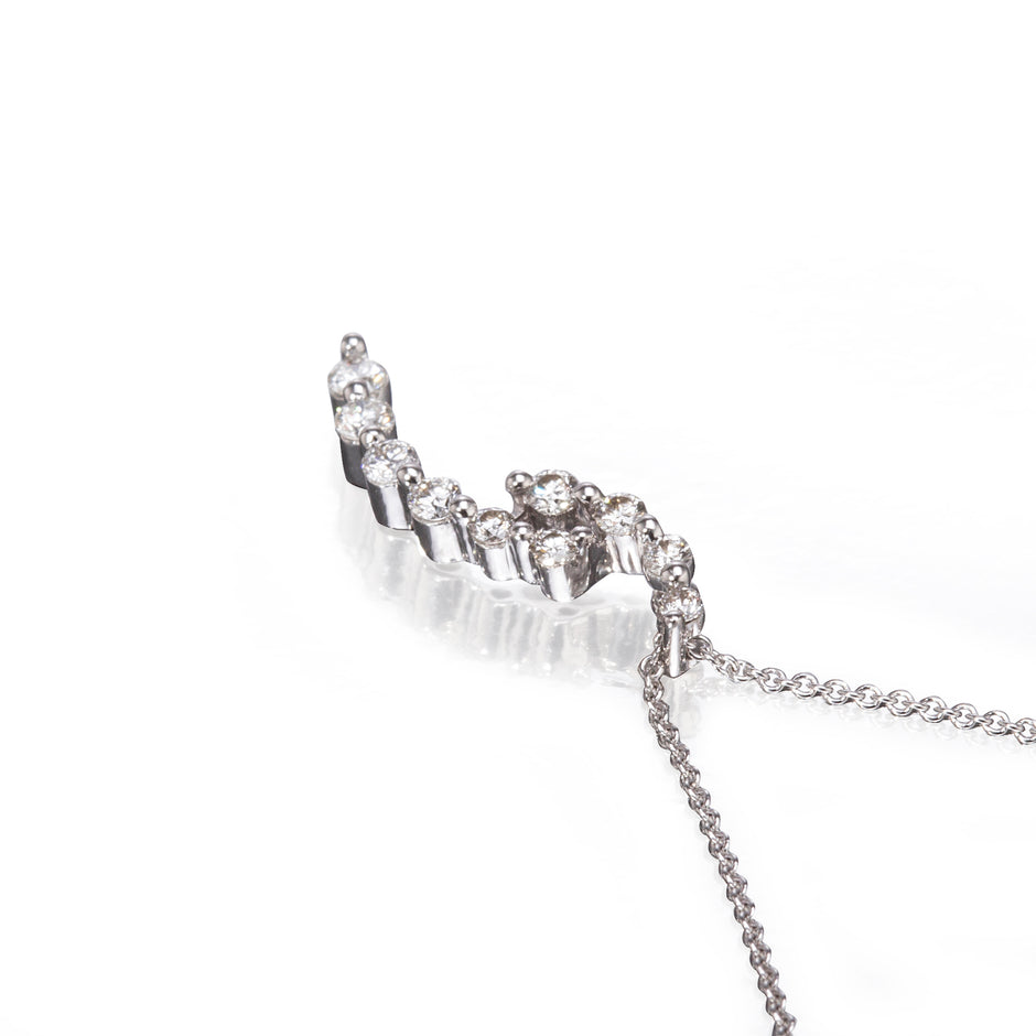 A white gold crescent-shaped necklace adorned with clear crystals, shown on a clean white background with a soft reflection.