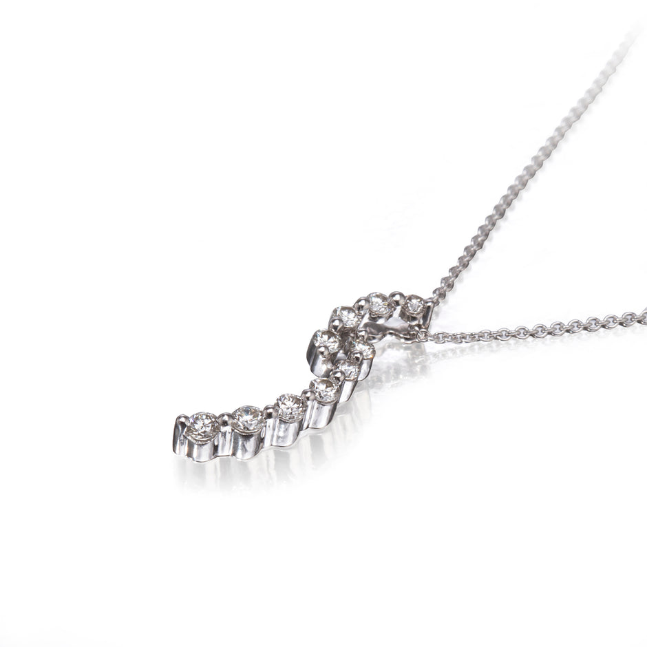 A white gold necklace with a curved, step-like pendant set with small clear gemstones, photographed on a clean white background with a soft reflection.