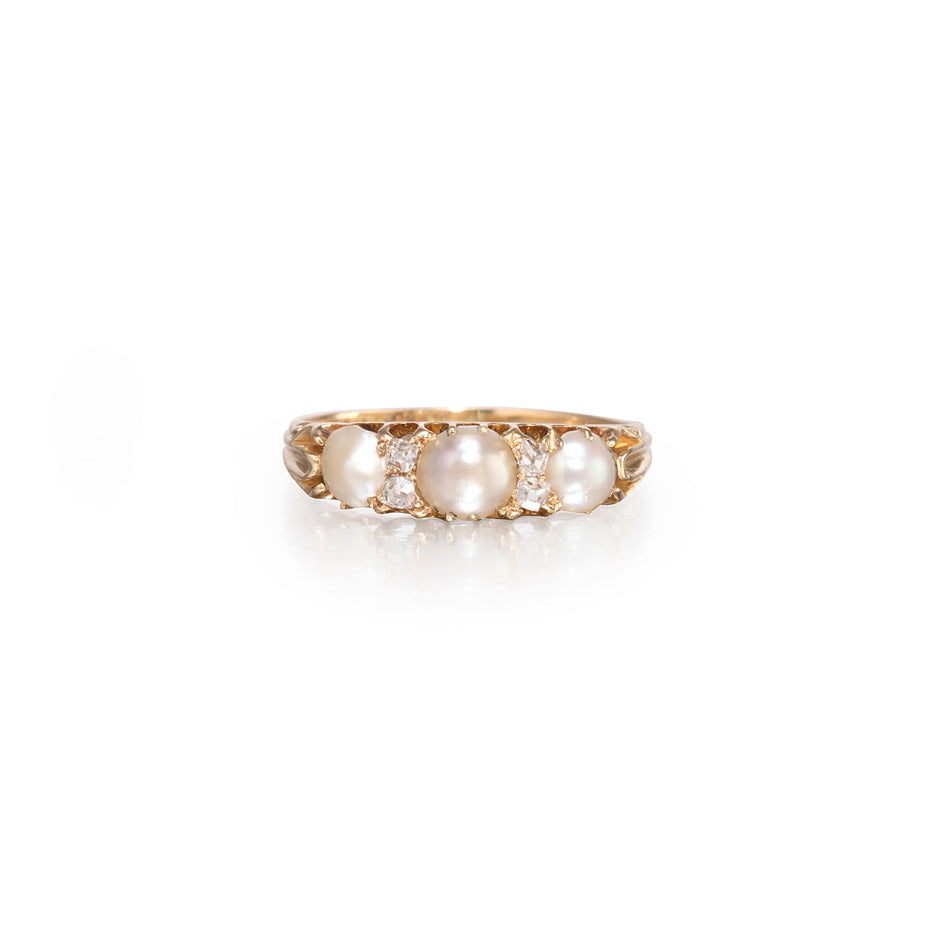 A vintage-style yellow gold ring featuring three large white pearls and small clear accent stones, set against a clean white background.