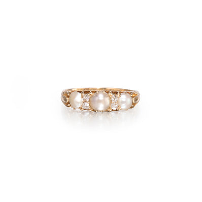 A vintage-style yellow gold ring featuring three large white pearls and small clear accent stones, set against a clean white background.