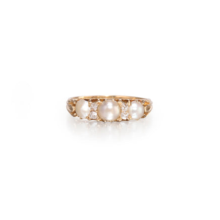 A vintage-style yellow gold ring featuring three large white pearls and small clear accent stones, set against a clean white background.