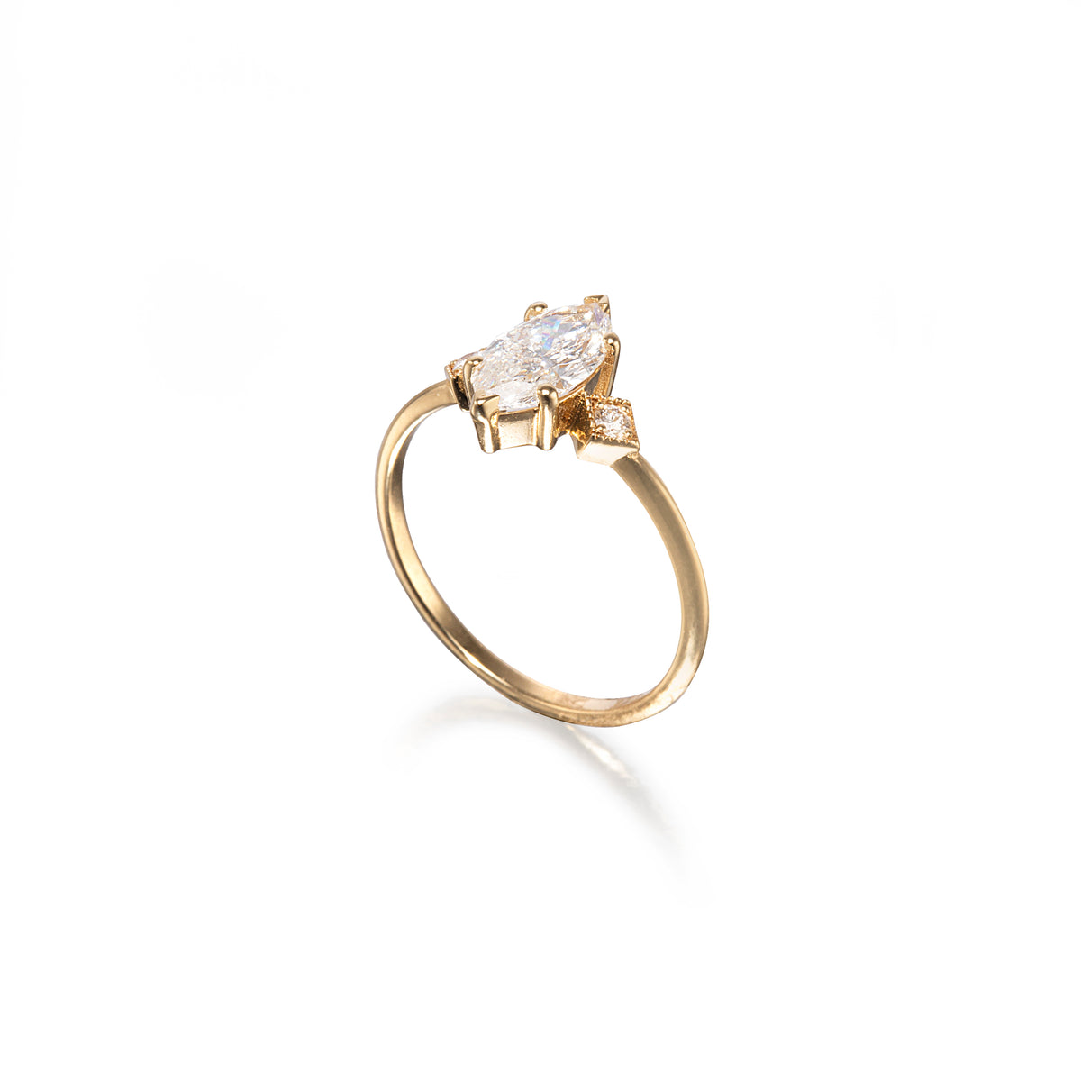 A yellow gold ring featuring a marquise-cut clear gemstone in a prong setting, with a small accent stone on the band, shown on a clean white background.