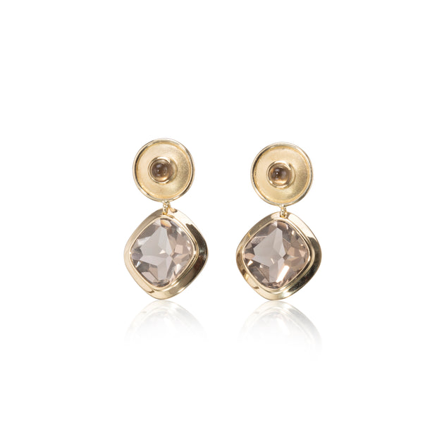 Gold earrings with clear gemstones on a white background