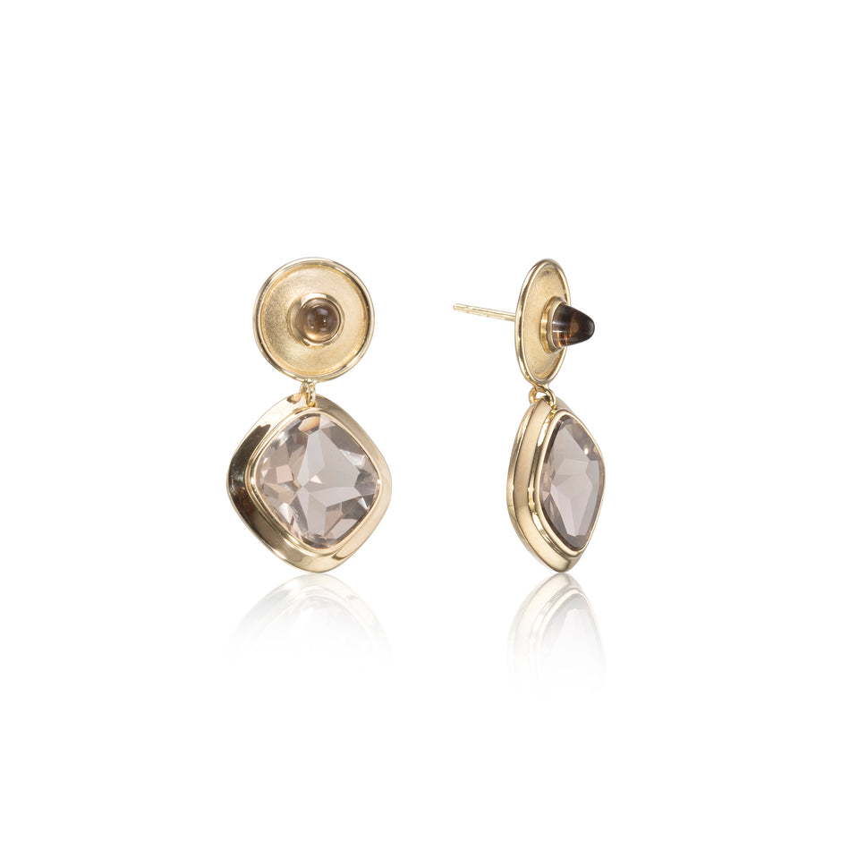 Gold earrings with clear gemstones on a white background