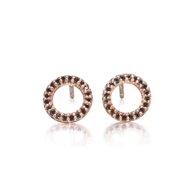 A pair of rose gold hoop stud earrings with a border of small black stones, shown on a clean white background with a soft reflection below.