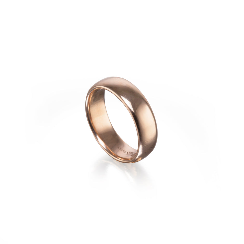 A polished rose gold band ring shown at an angle on a clean white background with a soft reflection underneath.