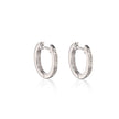 A pair of polished white gold huggie hoop earrings with small clear stones set along the front edge, displayed on a clean white background with a soft reflection below.