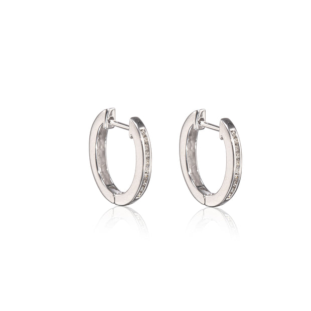 A pair of polished white gold huggie hoop earrings with small clear stones set along the front edge, displayed on a clean white background with a soft reflection below.