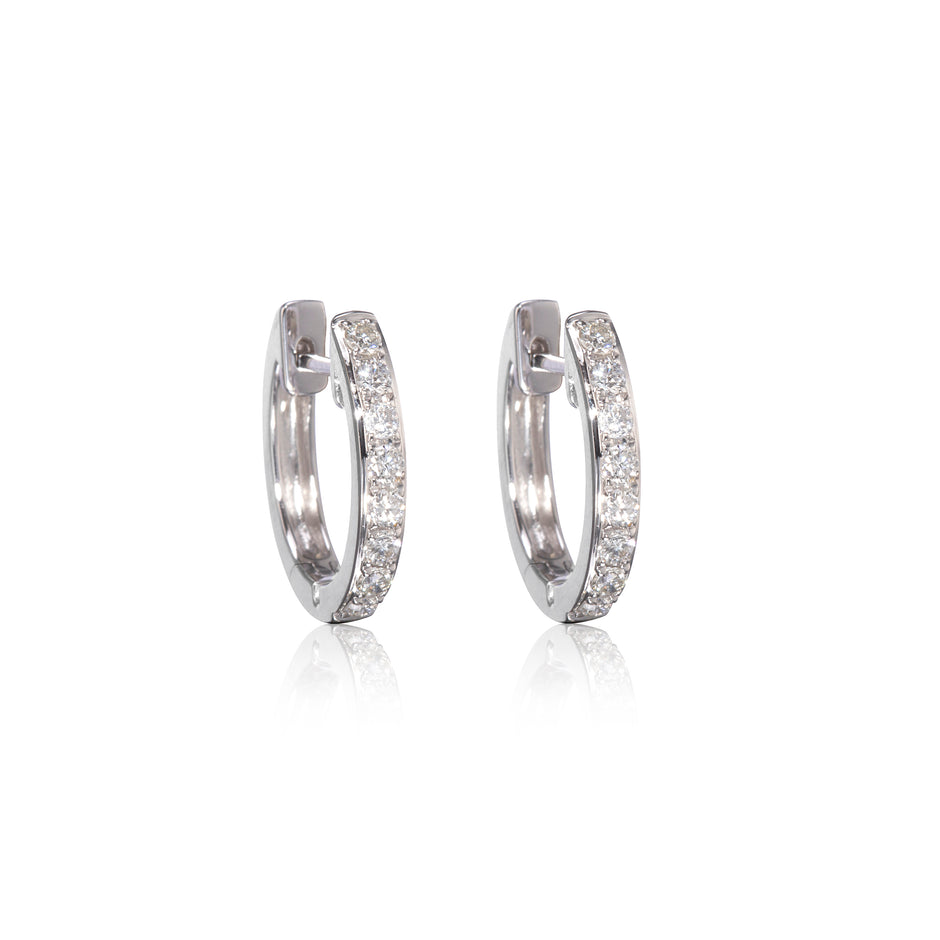 Pair of white gold diamond huggy earrings on a white background